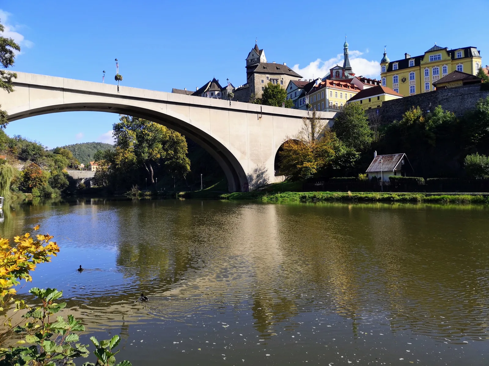 Betonbogenbrücke über die Eger, darüber Burg und Altstadt von Loket