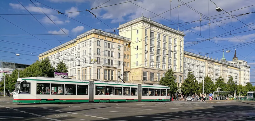Straßenbahn vor großen Wohn- und Geschäftshäusern in der Magdeburger Innenstadt
